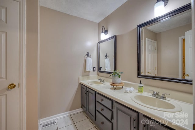 bathroom with double sink vanity, a textured ceiling, and tile patterned floors