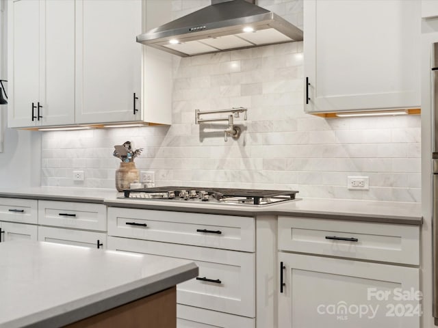 kitchen with white cabinetry, wall chimney range hood, and decorative backsplash