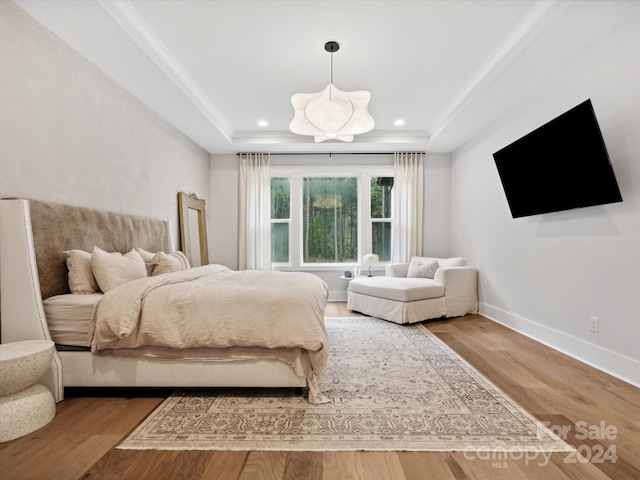 bedroom featuring hardwood / wood-style floors and a tray ceiling