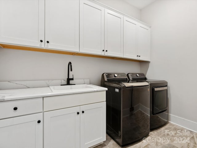 clothes washing area with cabinets, sink, and washing machine and clothes dryer