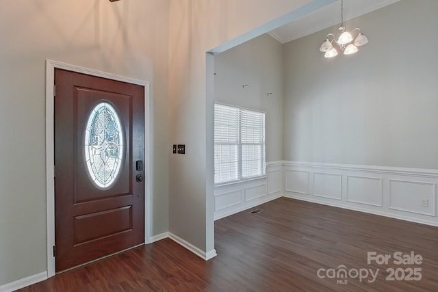 entrance foyer with dark hardwood / wood-style flooring, crown molding, and a notable chandelier