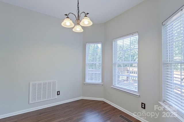 spare room featuring dark hardwood / wood-style flooring and a chandelier