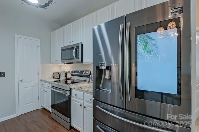 kitchen with hardwood / wood-style floors, stainless steel appliances, backsplash, light stone countertops, and white cabinets