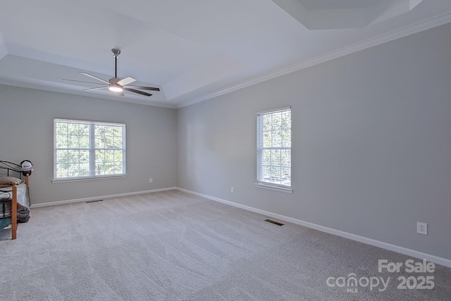 unfurnished room with ceiling fan, crown molding, a tray ceiling, and light carpet