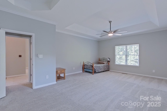 unfurnished bedroom with a tray ceiling, ornamental molding, and light carpet