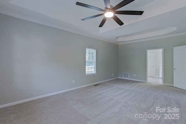 carpeted spare room with ceiling fan, a tray ceiling, and crown molding