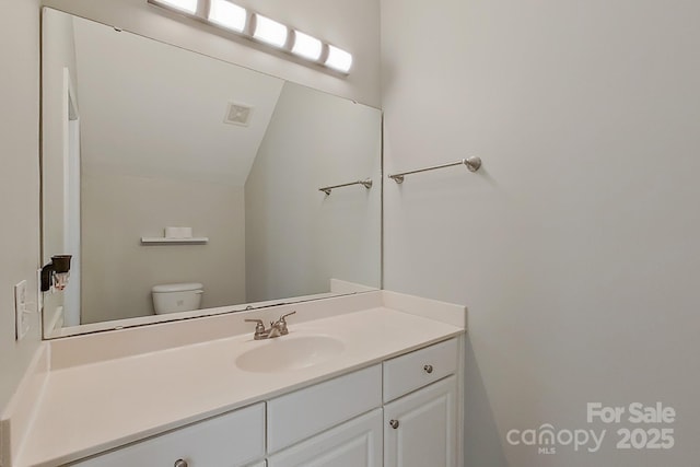 bathroom with toilet, lofted ceiling, and vanity