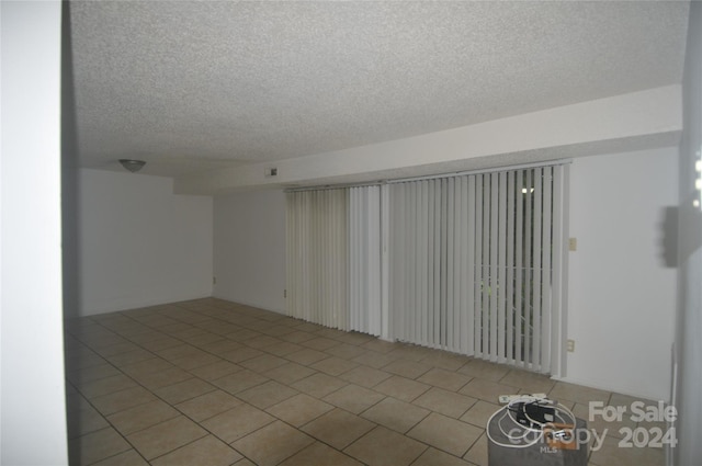 tiled empty room with a textured ceiling