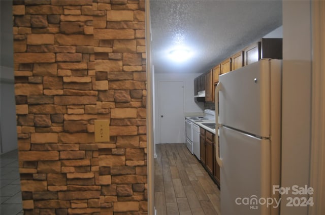 kitchen with a textured ceiling, white appliances, exhaust hood, and wood-type flooring