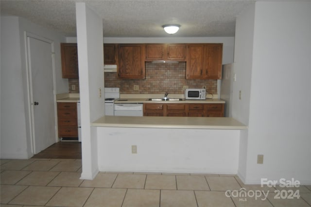 kitchen with sink, decorative backsplash, a textured ceiling, and light tile patterned floors