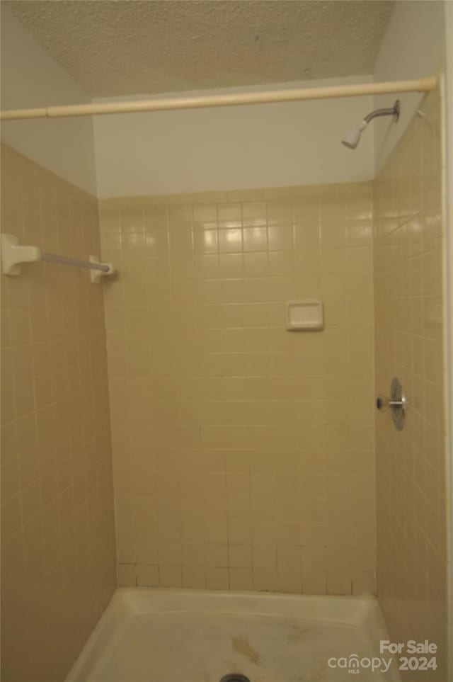 bathroom with a textured ceiling and a tile shower