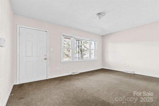 carpeted spare room with a textured ceiling