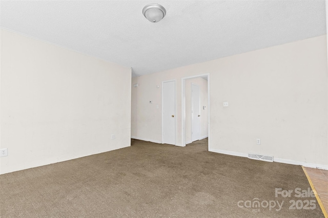 unfurnished room with dark carpet and a textured ceiling