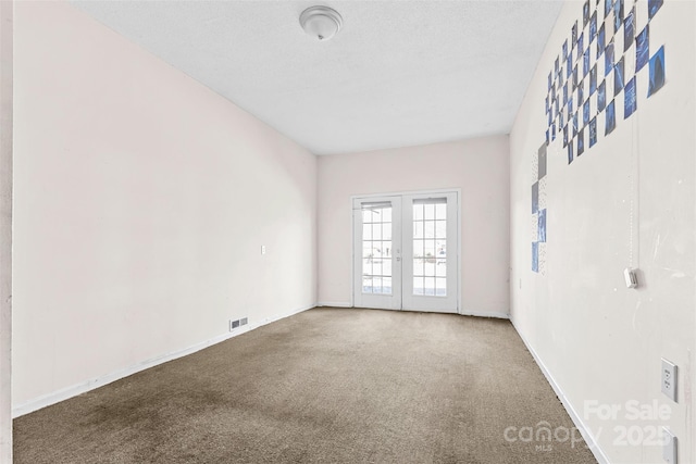 spare room featuring carpet flooring, french doors, and a textured ceiling