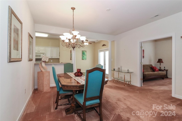 carpeted dining area featuring ceiling fan with notable chandelier and ornate columns