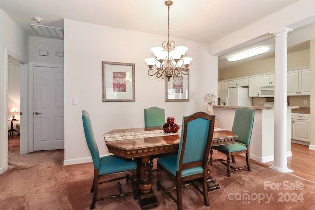 dining room with light hardwood / wood-style floors, an inviting chandelier, and ornate columns