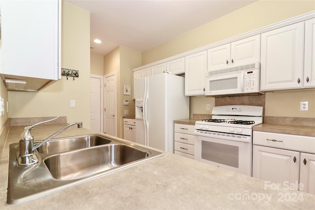 kitchen featuring sink, white appliances, and white cabinetry