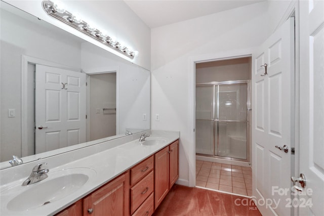 bathroom with hardwood / wood-style floors, a shower with door, and dual vanity