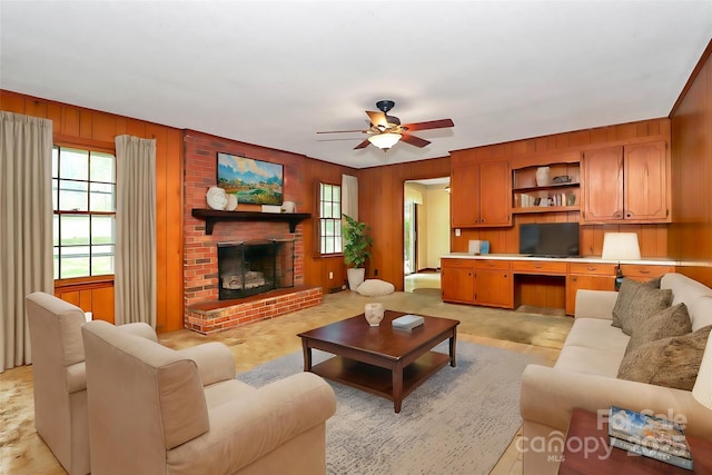 living room featuring a brick fireplace, plenty of natural light, ceiling fan, and built in desk