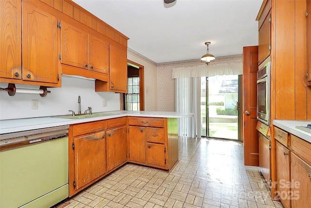 kitchen with oven, white dishwasher, sink, decorative light fixtures, and kitchen peninsula