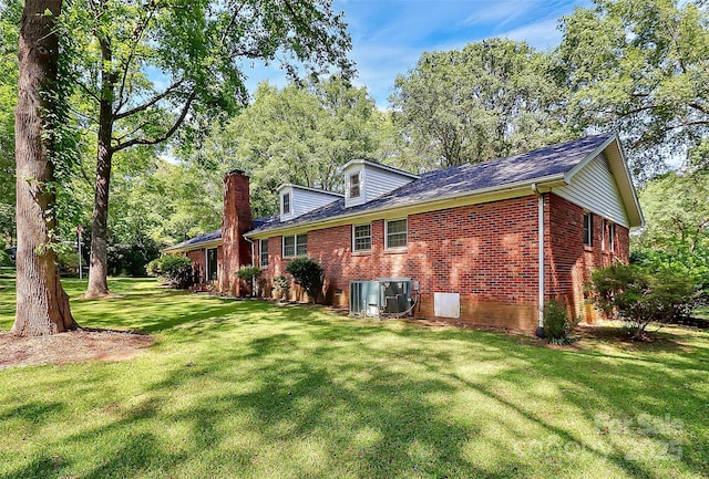 back of property with a lawn and central AC