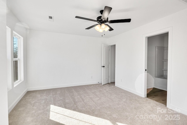 unfurnished bedroom featuring light carpet, ceiling fan, and connected bathroom