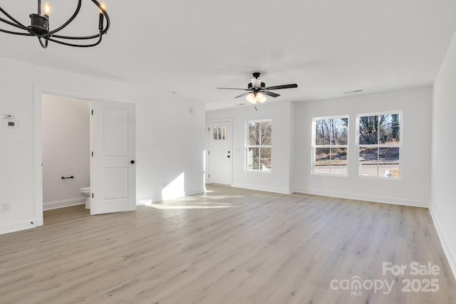 unfurnished living room featuring light wood-type flooring and ceiling fan with notable chandelier