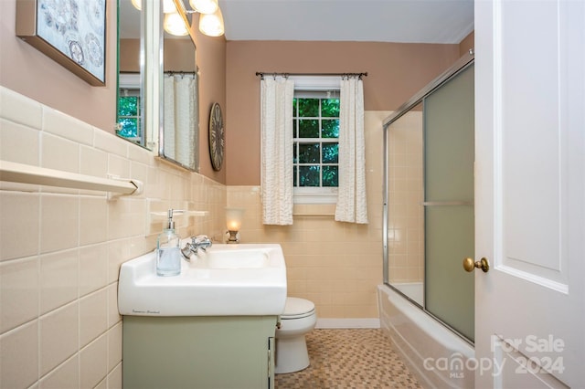 full bathroom featuring tile walls, vanity, shower / bath combination with glass door, and toilet