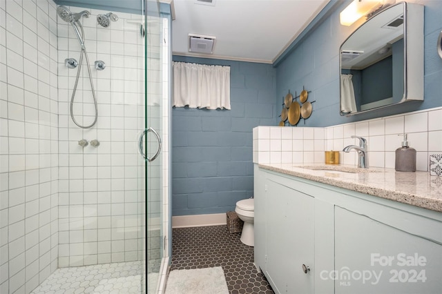 bathroom with a shower with door, vanity, ornamental molding, and toilet