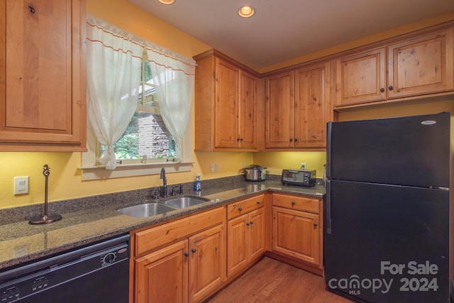 kitchen with sink, hardwood / wood-style floors, dark stone counters, and black appliances