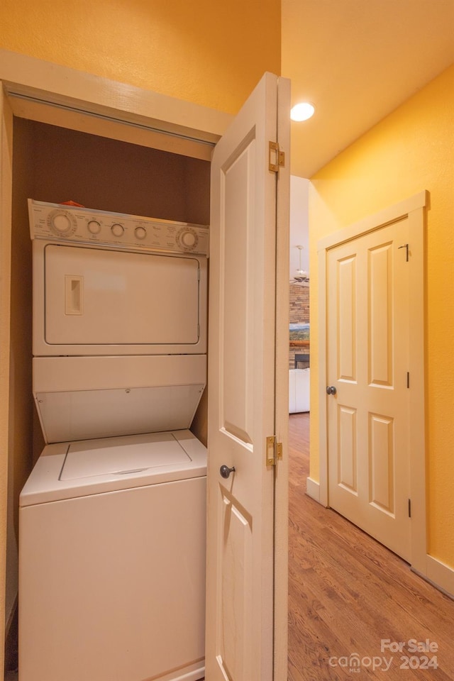 washroom featuring stacked washer and dryer and light hardwood / wood-style flooring