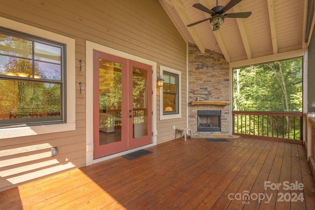 wooden terrace featuring a stone fireplace, ceiling fan, and french doors