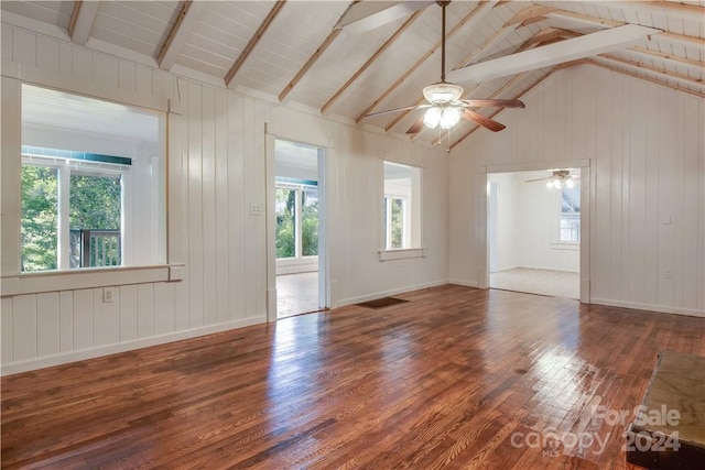 unfurnished living room with a wealth of natural light, ceiling fan, dark hardwood / wood-style flooring, and lofted ceiling with beams