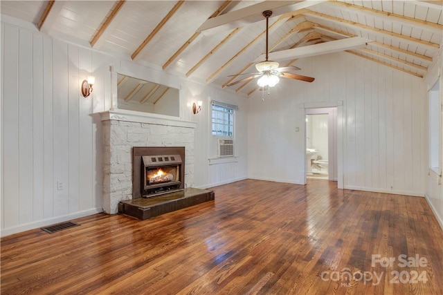 unfurnished living room featuring a fireplace, hardwood / wood-style flooring, lofted ceiling with beams, ceiling fan, and wooden walls