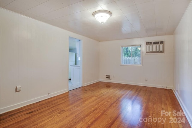 unfurnished room featuring a wall mounted AC and hardwood / wood-style flooring