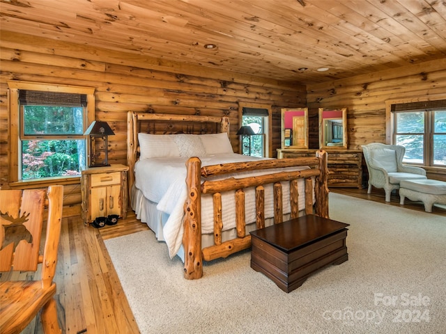 bedroom with log walls, light hardwood / wood-style floors, multiple windows, and wooden ceiling