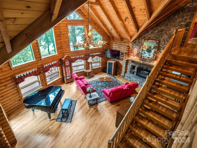 living room with wood-type flooring, beamed ceiling, wooden ceiling, a chandelier, and a stone fireplace