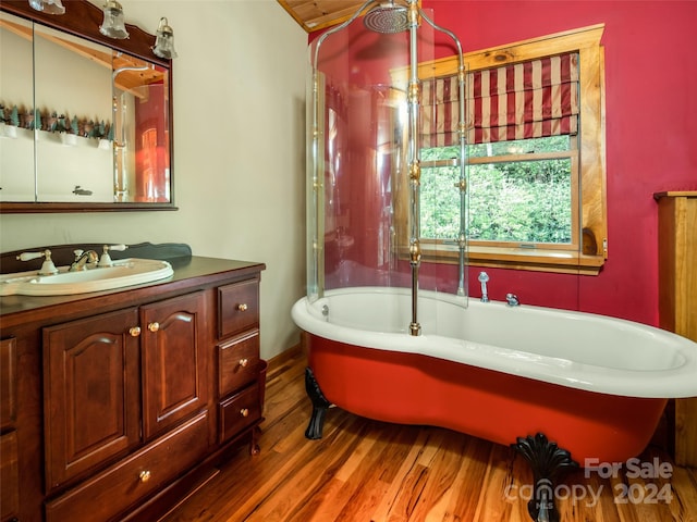 bathroom with vanity, wood-type flooring, and a bath