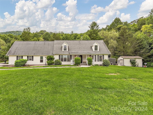 cape cod home with an outbuilding and a front lawn