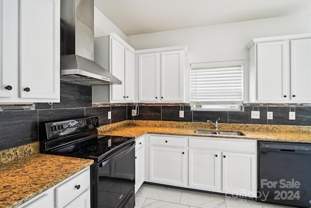 kitchen with white cabinetry, wall chimney range hood, dark stone counters, black appliances, and sink