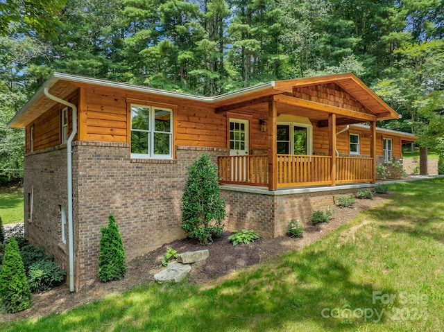 log cabin featuring a front yard and covered porch