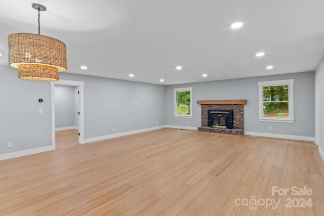 unfurnished living room featuring a brick fireplace and light hardwood / wood-style floors