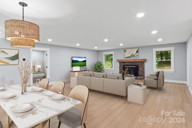 dining space with light hardwood / wood-style floors and a brick fireplace