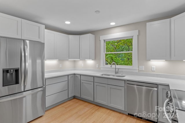 kitchen featuring sink, gray cabinetry, white cabinetry, appliances with stainless steel finishes, and light hardwood / wood-style floors