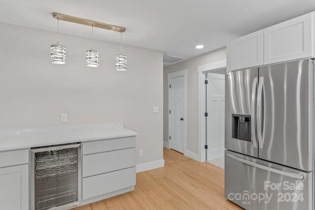 kitchen featuring wine cooler, stainless steel fridge with ice dispenser, hanging light fixtures, light hardwood / wood-style floors, and white cabinets