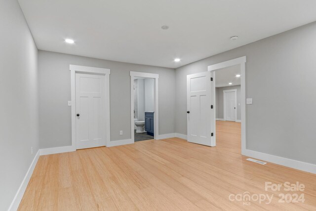 unfurnished bedroom with light wood-type flooring and ensuite bathroom