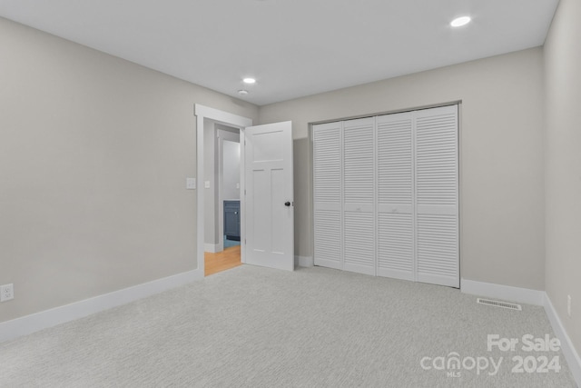 unfurnished bedroom with a closet and light carpet