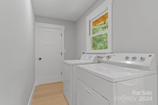 clothes washing area with washing machine and clothes dryer and light hardwood / wood-style floors