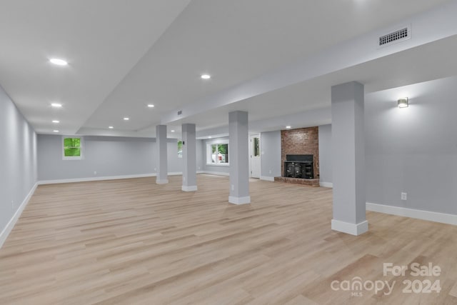 basement with a brick fireplace and light hardwood / wood-style flooring