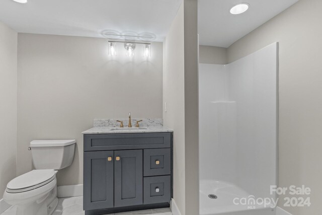 bathroom with vanity, a shower, toilet, and tile patterned flooring